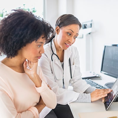 Doctor explaining health needs with patient with tablet